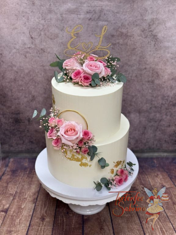 Hochzeitstorte - Rosa und gold sind die beiden Hauptfarben der Torte. Kleine und große rosa Rosen sind neben den goldenen Ring platziert.