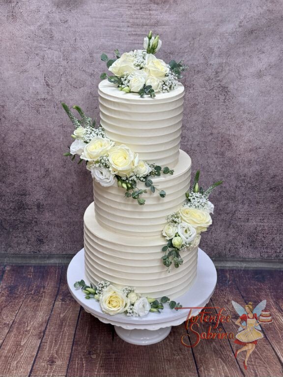 Hochzeitstorte - Rosen und Rillen verzieren die dreistöckige Anlasstorte wechle gezielt darauf in Szense setzt.