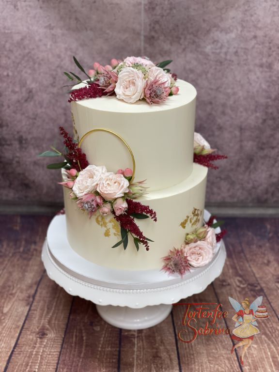 Hochzeitstorte - Rote Astilben mit rosa Rosen verzieren neben dem goldenen Ring und dem Blattgold die zweitöckige Torte.