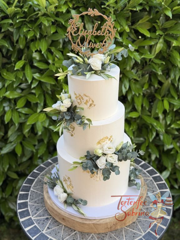 Hochzeitstorte - Schimmerndes Gold in Form von Blattgold verziert die dreistöckige Torte neben weißen Lisiantus.