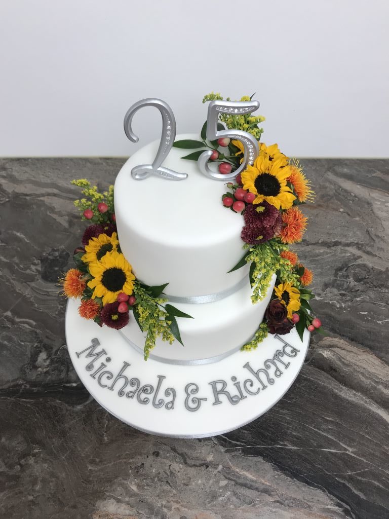 Hochzeitstagstorte - Silberne 25ig ziert die obere Torte in Form eines Cake Toppers. Die Torte wurde ebenfalls mit echten Blumen dekoriert.
