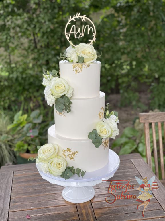 Hochzeitstorte - Üppige weiße Rosen verzieren neben Blattgrün, Lisianthus und Blattgold die dreistöckige Torte.