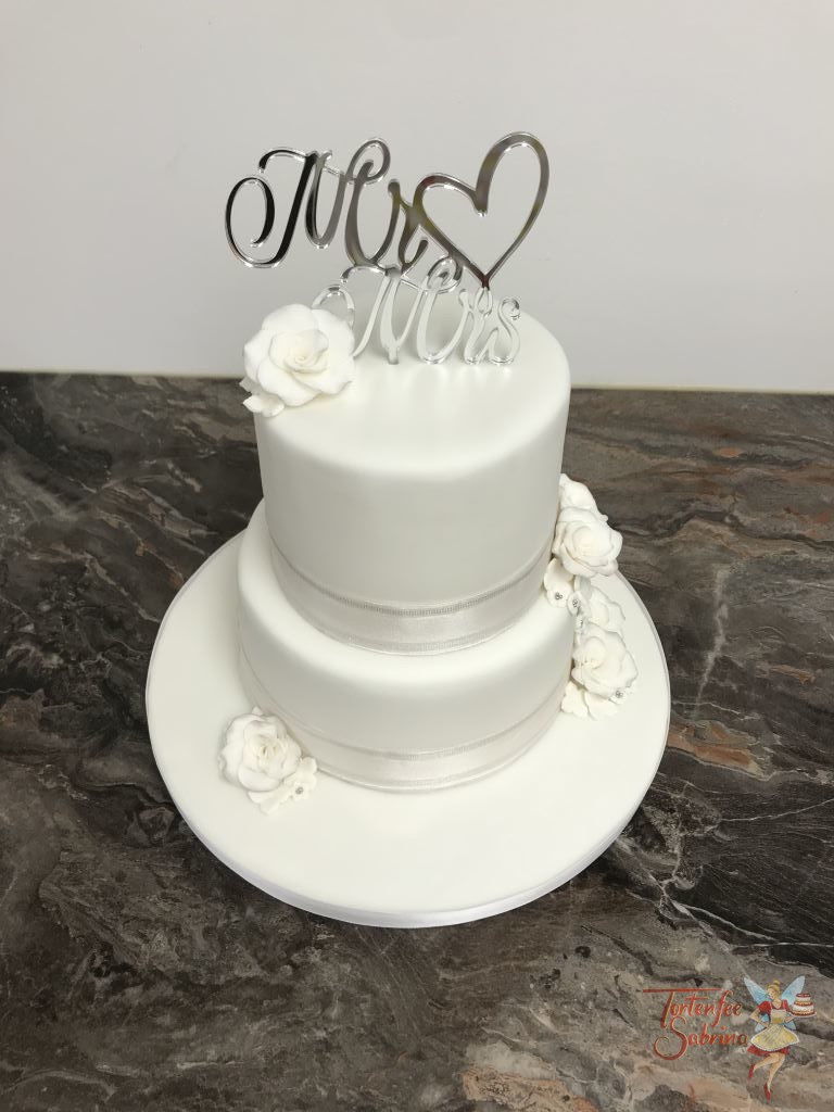 Hochzeitstorte - Weiß mit Rosen und einem schönen Band. Den oberen Abschluß bildet ein schöner Cake Topper in silber.