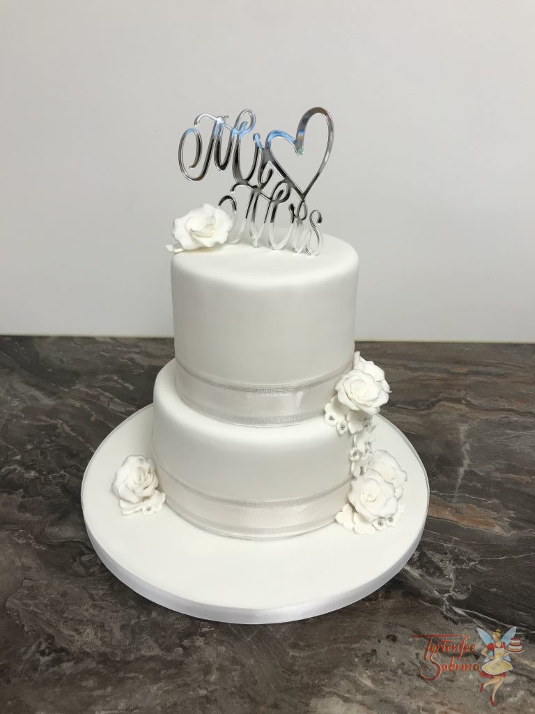 Hochzeitstorte - Weiß mit Rosen und einem schönen Band. Den oberen Abschluß bildet ein schöner Cake Topper in silber.