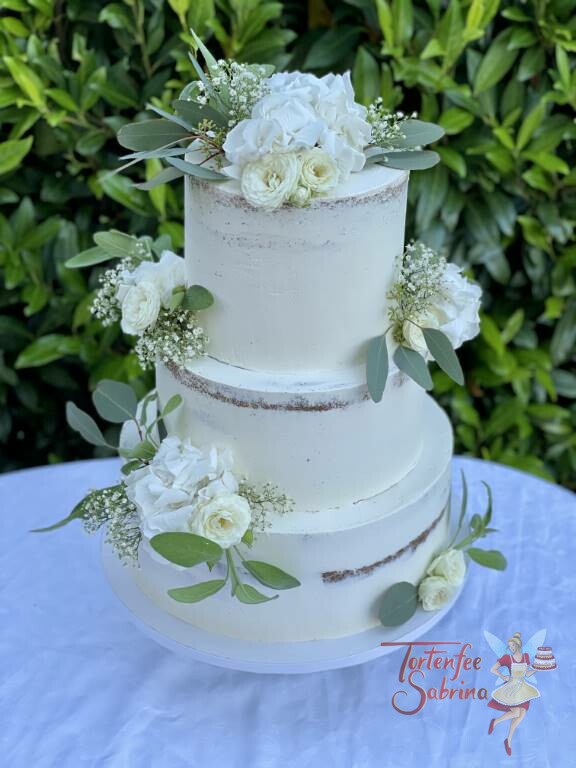 Hochzeitstorte - Weiße Blumen und grüne Blätter wurden auf der 3-stöckigen an verschiedenen Stellen drapiert.