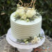 Hochzeitstorte - Weiße Rillen verzieren seitlich die Torte, oben bilden Rosen, Blattgrün sowie der Caketopper aus Holz den Abschluß.