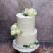 Hochzeitstorte - Weiße Rillen verzieren beide Etagen der Torte, neben den schönen weißen Rosen und dem goldenen Caketopper.