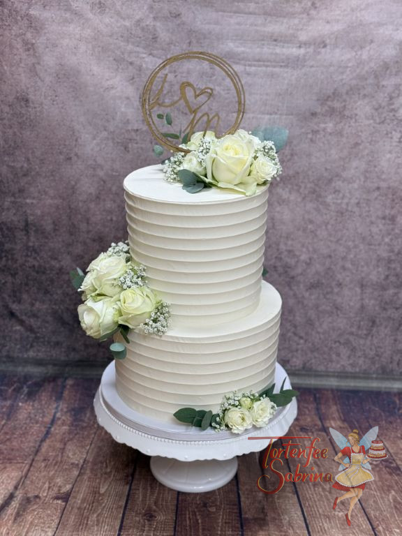 Hochzeitstorte - Weiße Rillen verzieren beide Etagen der Torte, neben den schönen weißen Rosen und dem goldenen Caketopper.