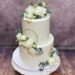 Hochzeitstorte - Weiße Rosen mit goldenem Ring und Blattgold verzieren die weiße zweistöckige Torte mit Caketopper.