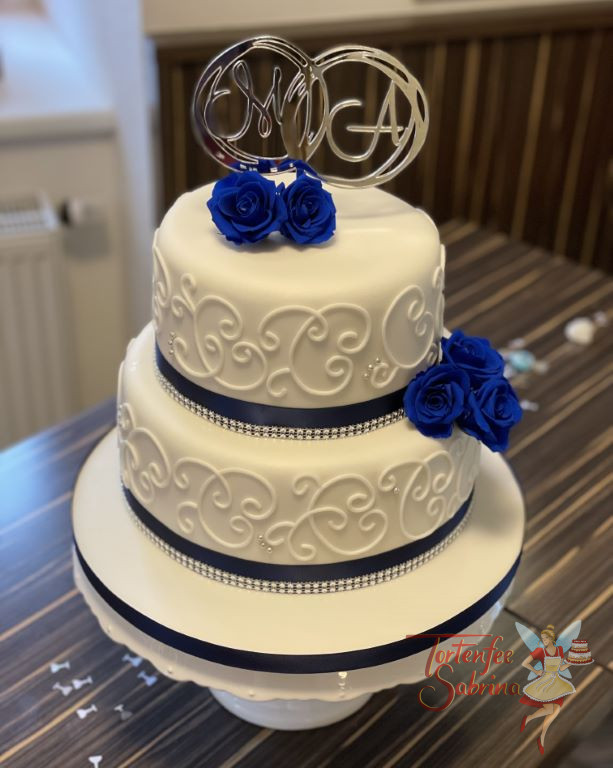 Hochzeitstorte - Weiße Schnörkel mit getrockenten blauen Rosen, dazu als Abschluß ein blaues Band und ganz oben der Caketopper.