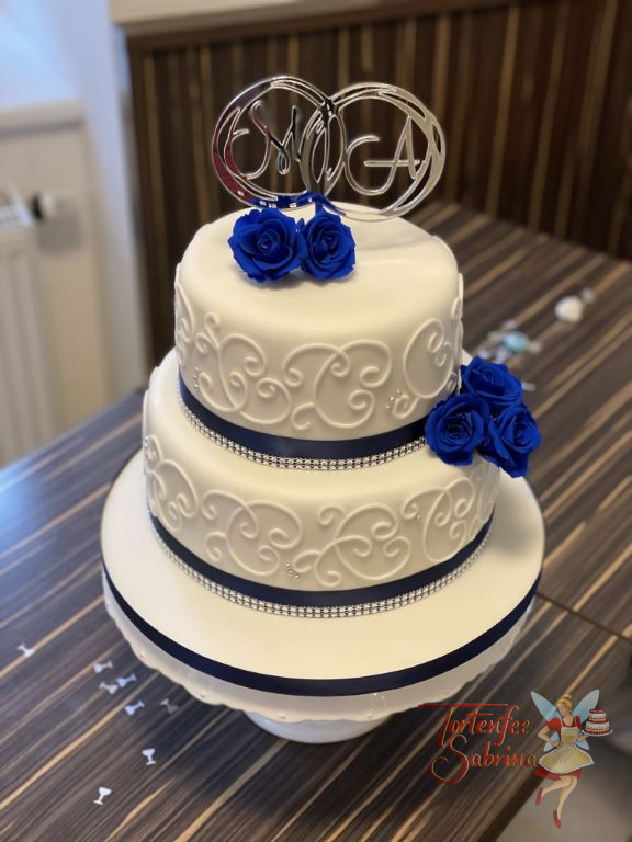Hochzeitstorte - Weiße Schnörkel mit getrockenten blauen Rosen, dazu als Abschluß ein blaues Band und ganz oben der Caketopper.