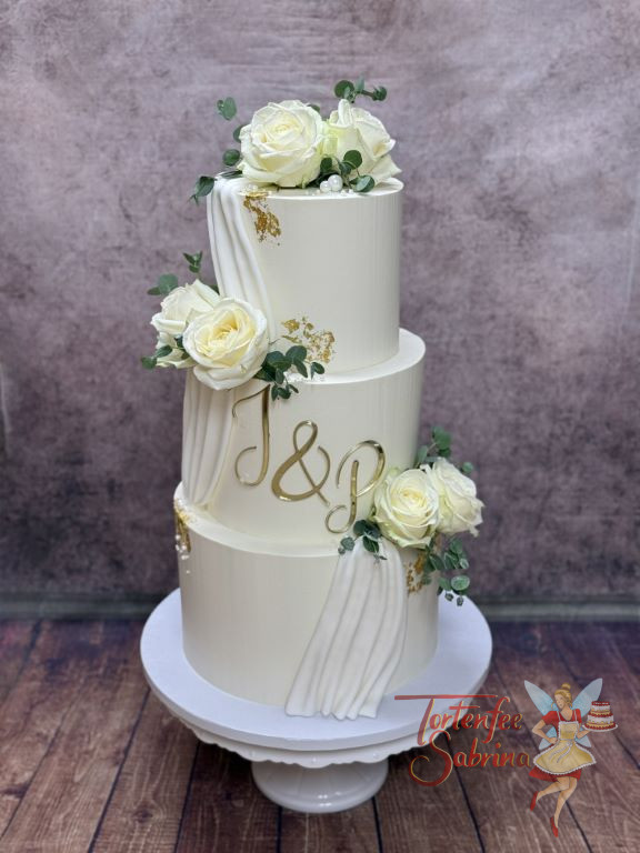 Hochzeitstorte - Weißer Schleier aus Fondant verziert die drei Etagen der Torte, ganz vorne in der Mitte ist der goldene Fronttopper.