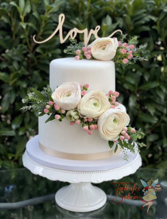 Hochzeitstorte - Zart rosa Ranunkeln in verschiedenen Größen, ganz oben ziert die Torte ein Cake Topper mit der Aufschrift Love.