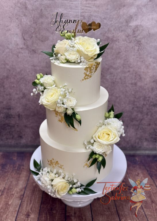 Hochzeitstorte - Zwei goldene Herzen stehen neben den beiden Namen des Brautpaares in goldener Farbe ganz oben auf der Torte.
