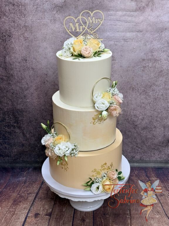 Hochzeitstorte - Zwei goldene Ringe verzieren neben den Blumen, Blattgold und dem Caketopper aus Holz die Torte.