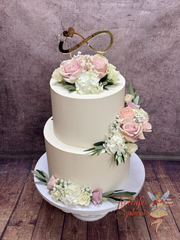 Hochzeitstorte - Zwei kleine Herzen verzieren neben der Schleife und den Namen die weisse zweistöckige Torte.
