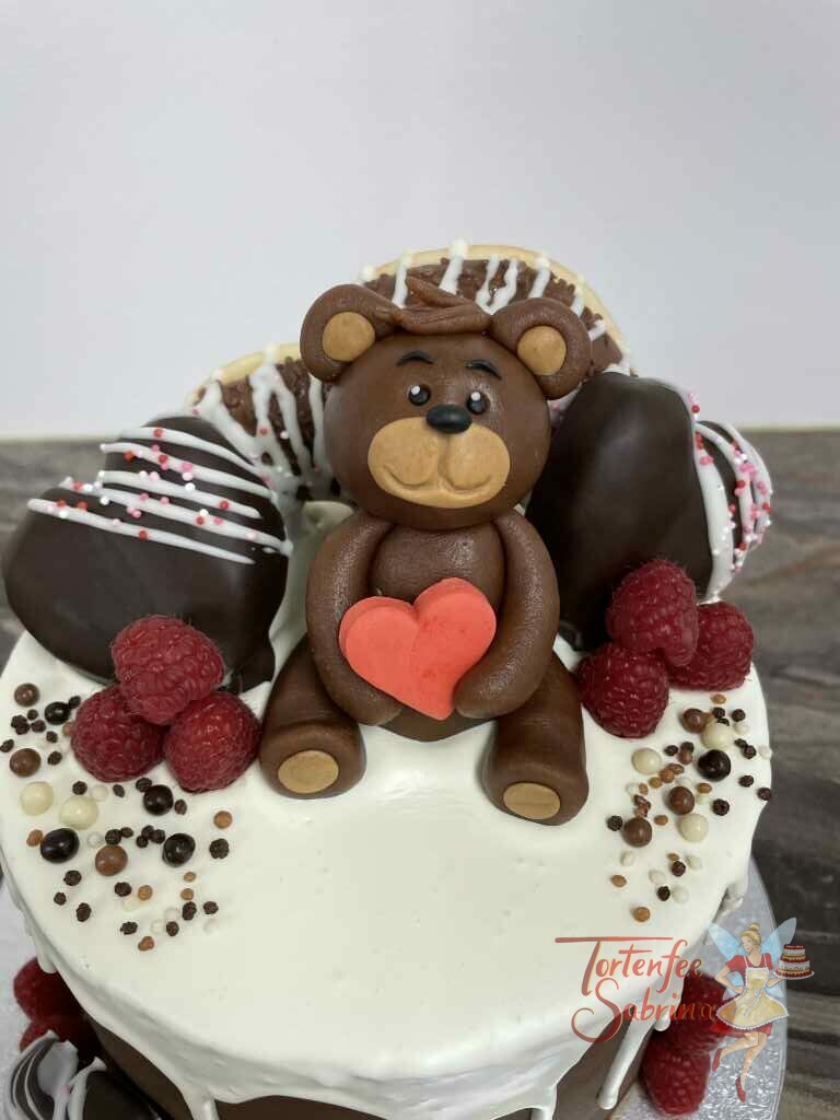 Jahrestagstorte - Bär mit Schokoherzen, hier sitzt der Marzipan-Bär auf einer Decke aus weißer Schokolade mit seinem roten Herzen.