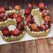 Number Cake - Macarons und Rosen in roter Farbe verzieren die Torte in Form einer 50ig, zusätlich mit roten Früchten.