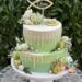Tauftorte - Baby auf grüner Decke und weißem Drip, zusätzlich wurde die Torte noch mit Cake Pops und Macarons dekoriert.