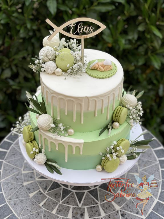 Tauftorte - Baby auf grüner Decke und weißem Drip, zusätzlich wurde die Torte noch mit Cake Pops und Macarons dekoriert.