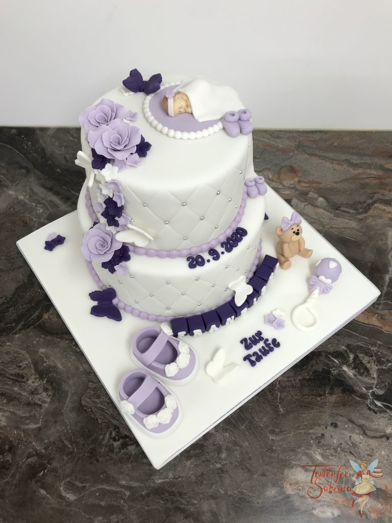 Tauftorte - Baby in lila und violett mit Schuhen und Blumen. Den Rand der beiden Torten ziert ein Rautenmuster und Perlen.