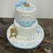 Tauftorte - Baby mit blauen Rosen, weiters auf der Torte sitze ein Bär mit blauem Herz. Ebenso ist ein Kreuz und ein Schleife auf der Torte.