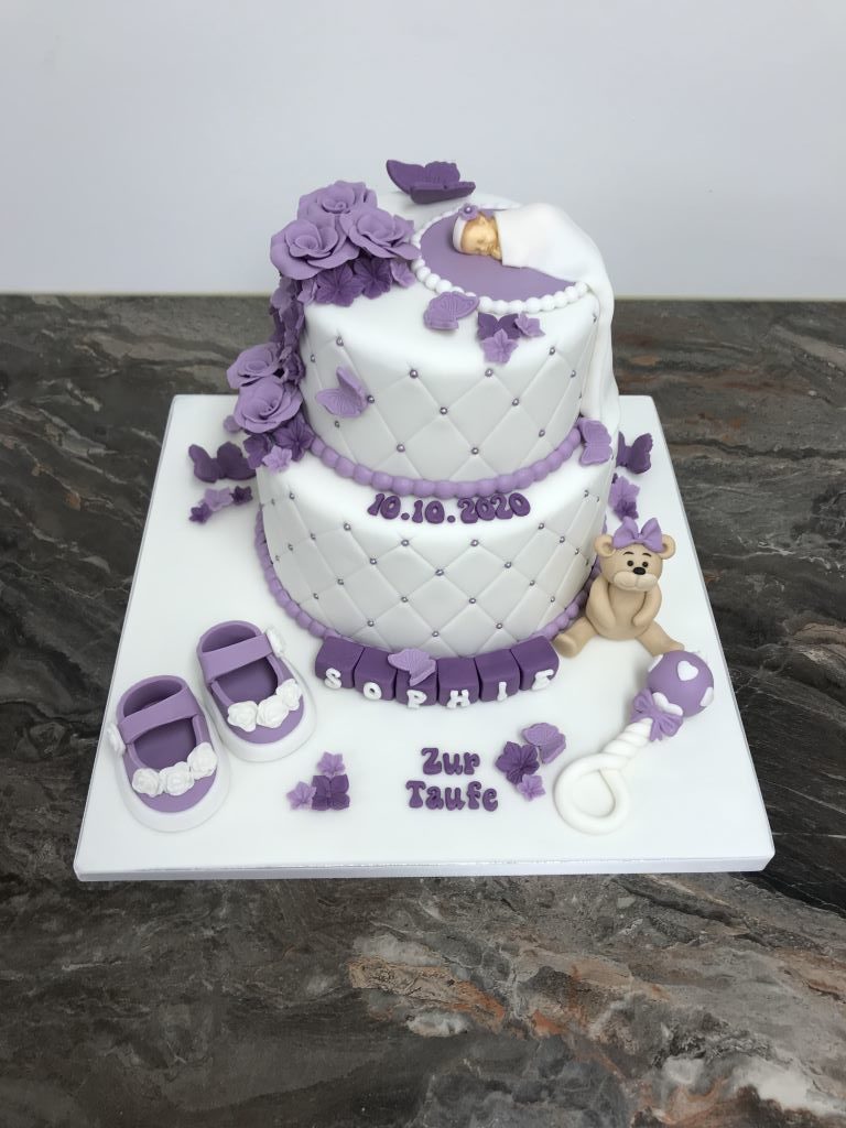 Tauftorte - Baby mit lila und violetten Blumen. Diese Torte wurde mit einem Bär, Rassel und Schüchen verziert.