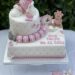 Tauftorte - Bär mit rosa Herzchen sitzt auf der Torte zwischen einer Uhr, Gewichten und einem Maßband, sowie den Namenswürfeln.