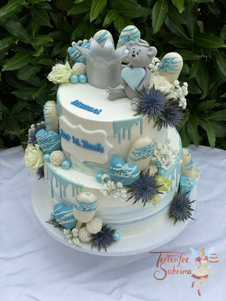 Tauftorte - Bär mit silberner Krone ist ganz oben auf der Torte und hält ein blaues Herz zwischen Blumen und Süßigkeiten.