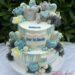 Tauftorte - Bär mit silberner Krone ist ganz oben auf der Torte und hält ein blaues Herz zwischen Blumen und Süßigkeiten.