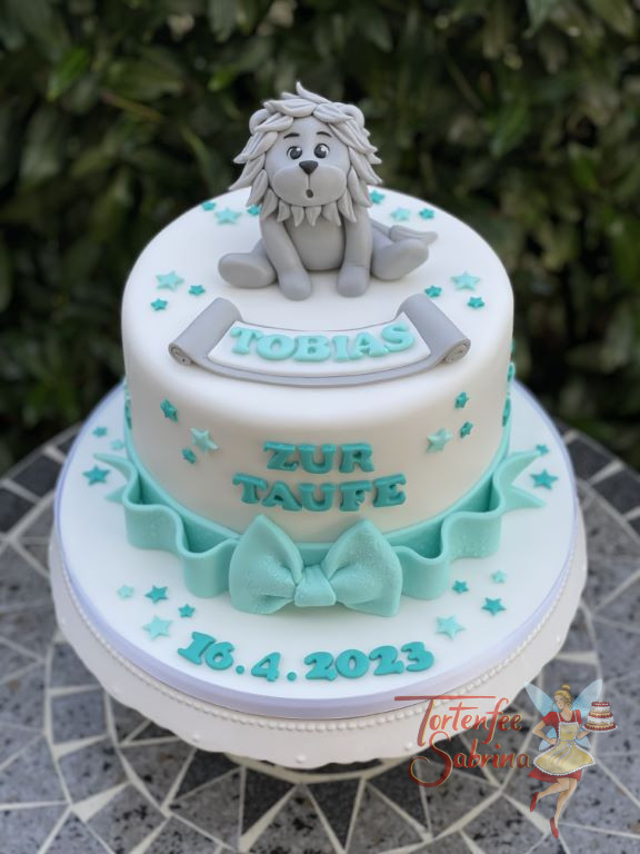 Tauftorte - Der entzückende Löwe in grauer Farbe ist ganz oben auf der Torte umgeben von türkisen Sternen und einer Schleife.