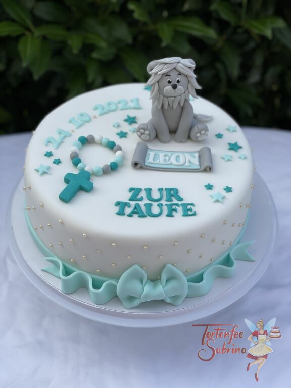 Tauftorte - Der graue Löwe sitzt stolz auf seiner Torte umgeben von türkisen Sternen und einem Kreuz mit Perlenkette.