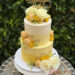 Tauftorte - Gelbe Macarons und gelbe Blumen verzieren neben Blattgold und dem Caketopper aus Holz die Torte.