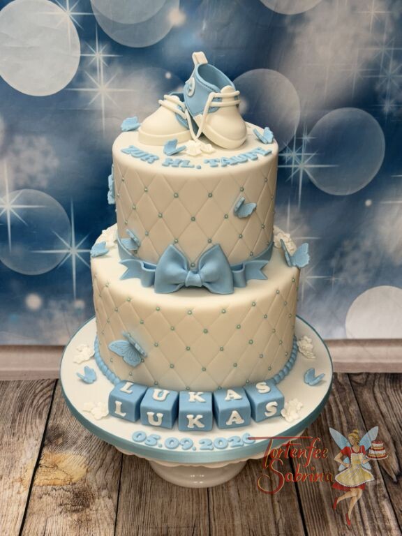 Tauftorte - Hellblaue Schmetterlinge, Schleife und Schuhe verzieren die zweistöckige Torte mit detailliertem Rautenmuster.