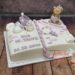 Tauftorte - Kleine lila Schleife sitzt zwischen den Ohren des Teddybären, welcher neben den beiden Schuhen die Torte verziert.
