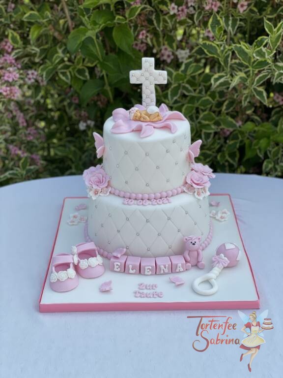 Tauftorte - Kreuz mit Perlen und Baby auf einer Blüte. Auf der Torte sind ebenfalls noch Blumen, ein Kreuz und Babyschuhe.