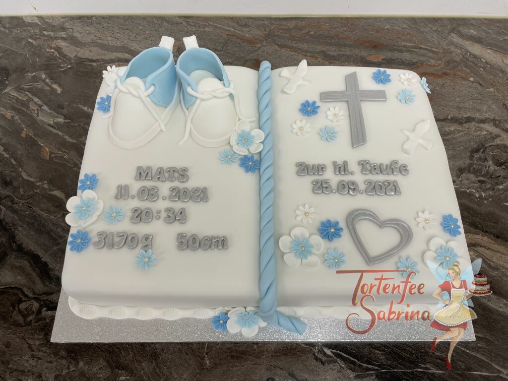 Tauftorte - Taufbuch mit silbernem Herzen und Kreuz, ebenfalls auf dem sind blaue Schüchen und Blumen in den Farben weiß und blau.