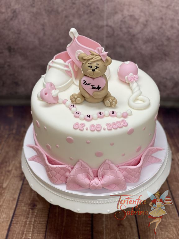 Tauftorte - Teddybär mit großer Schleife auf dem unteren Abschluss der Torte, ebenso sind Schuhe und Rassel auf der Torte.