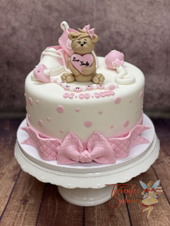 Tauftorte - Teddybär mit großer Schleife auf dem unteren Abschluss der Torte, ebenso sind Schuhe und Rassel auf der Torte.
