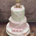 Tauftorte - Zauberhaftes Bärchen ist ganz oben auf der zweistöckigen Torte und hält ein rosa Herzchen in seinen Tatzen.